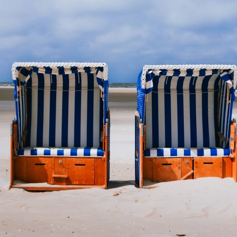Badespass an der Nordsee Zwei Strandkörbe mit blauen und weißen Streifen auf einem Sandstrand.